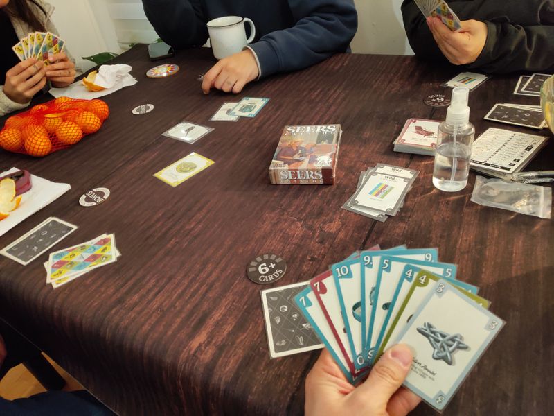 Five people playing Seers Catalog around a table