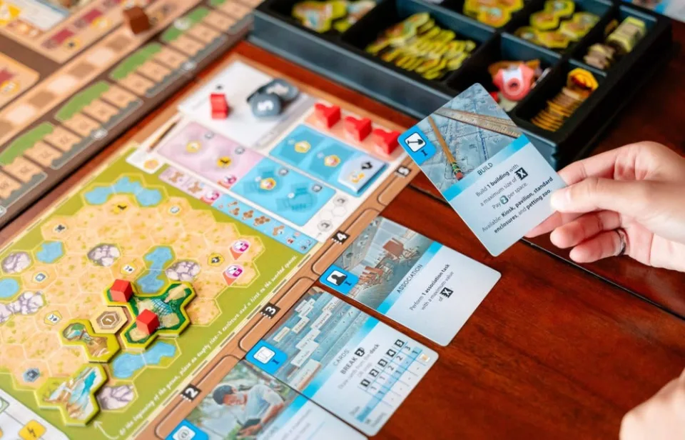 Ark Nova player boards, action cards, card decks, and black component tray on a table