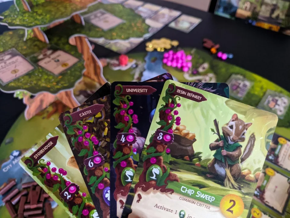 Everdell player cards held over a game board