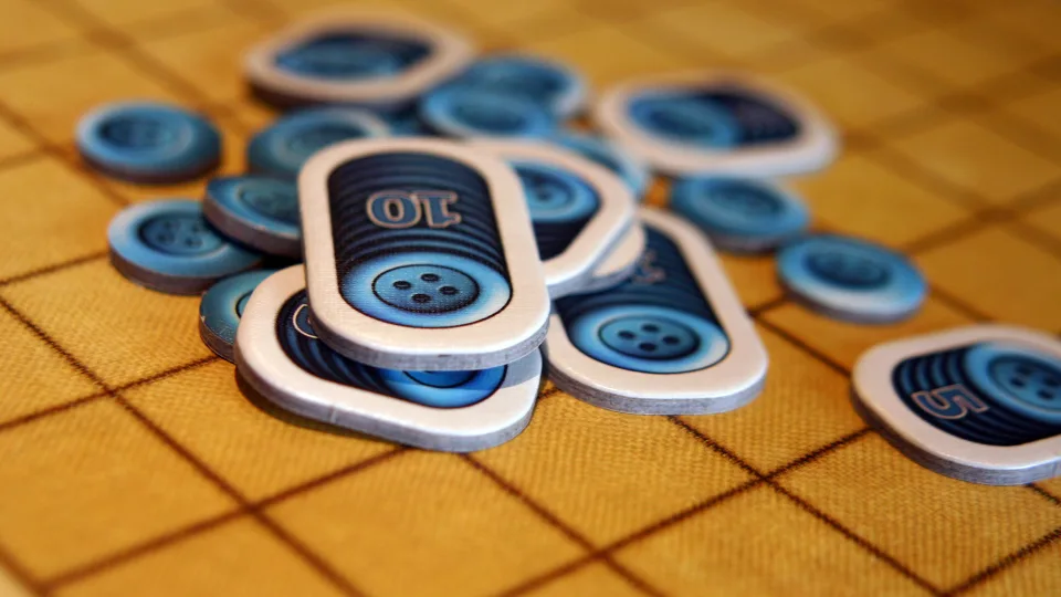 Patchwork blue button currency tokens on a quilt board.