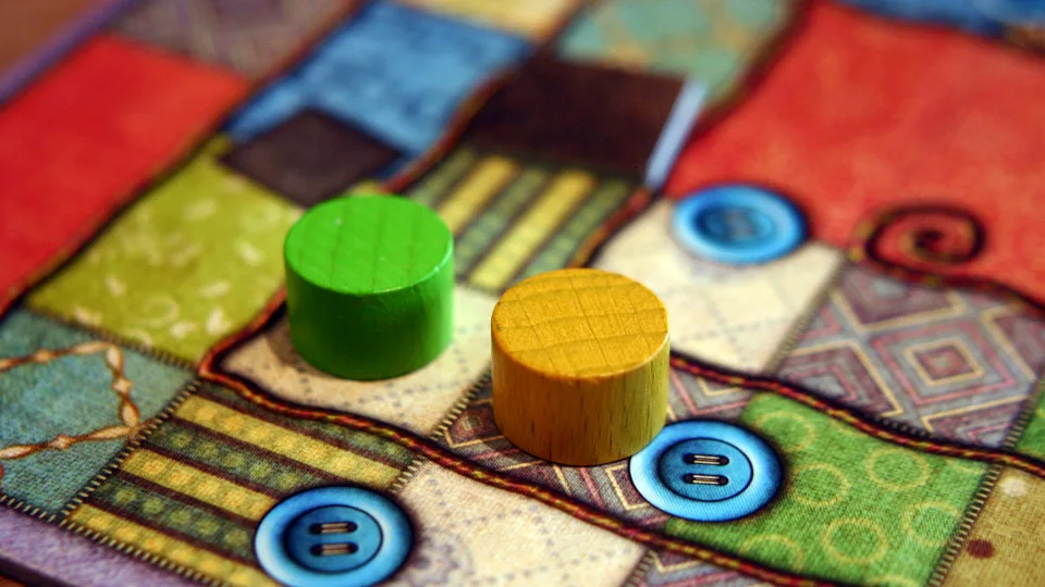 Patchwork green and yellow wooden player pieces on patch tiles.