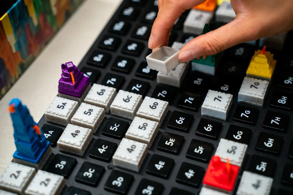 Player placing a building tile on the Acquire game board